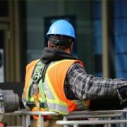Trabajador de construcción con casco azul y chaleco de seguridad en obra en Miami.