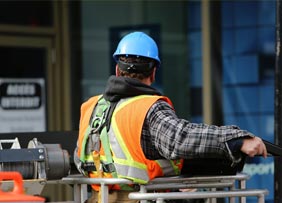 Trabajador de construcción con casco azul y chaleco de seguridad en obra en Miami.