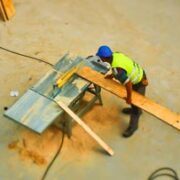 Trabajadores en sitio cortando madera para proyecto de construcción.