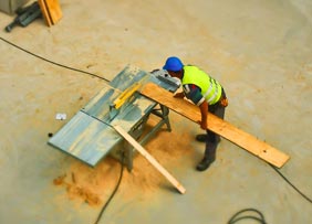 Trabajadores en sitio cortando madera para proyecto de construcción.