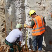 Trabajadores en obra realizando tareas de construcción en pared de concreto.