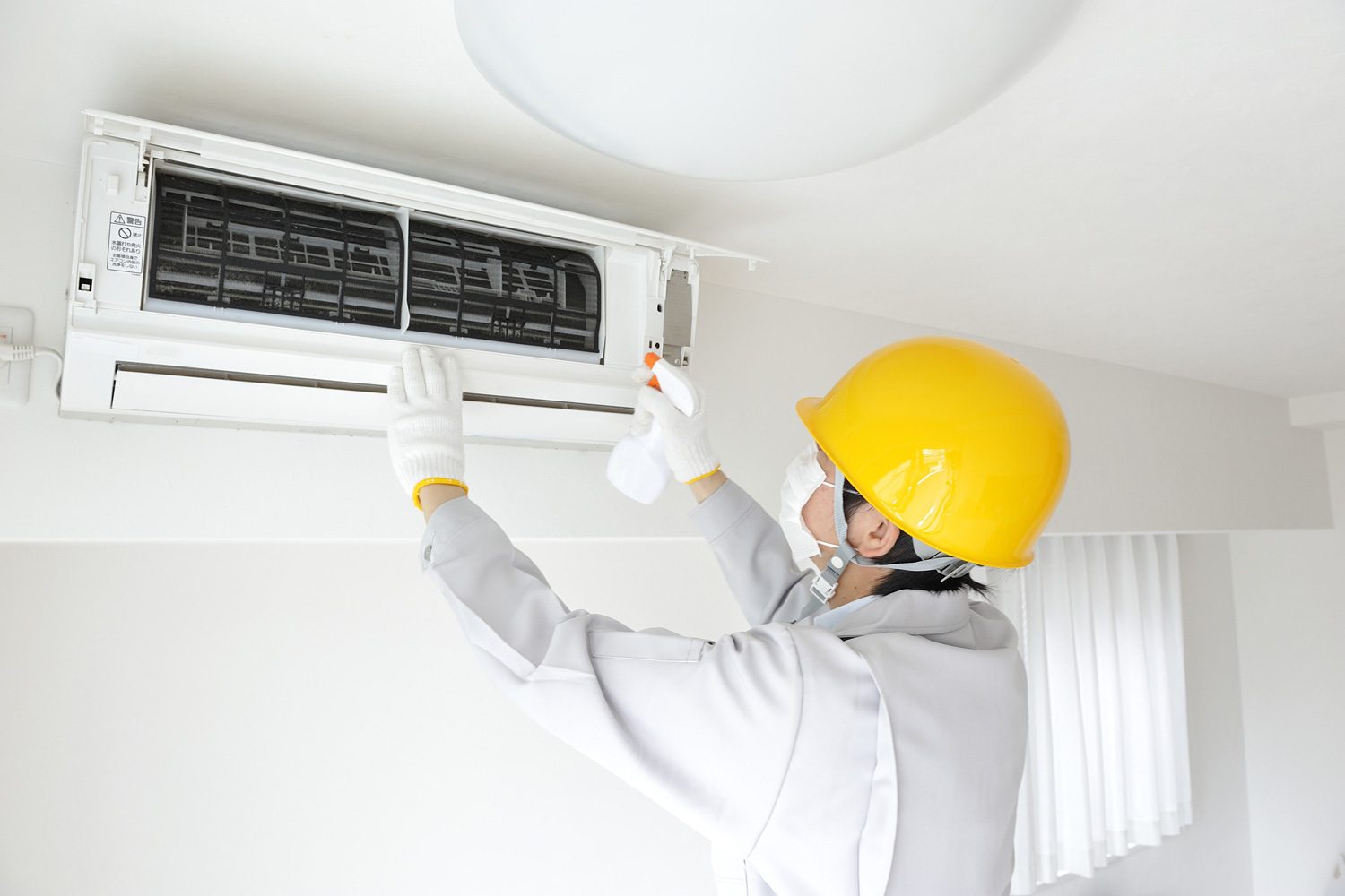 Técnico limpiando unidad de aire acondicionado en interior.